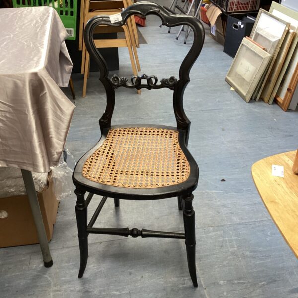 Black Gothic bedroom chair with woven cane seat.