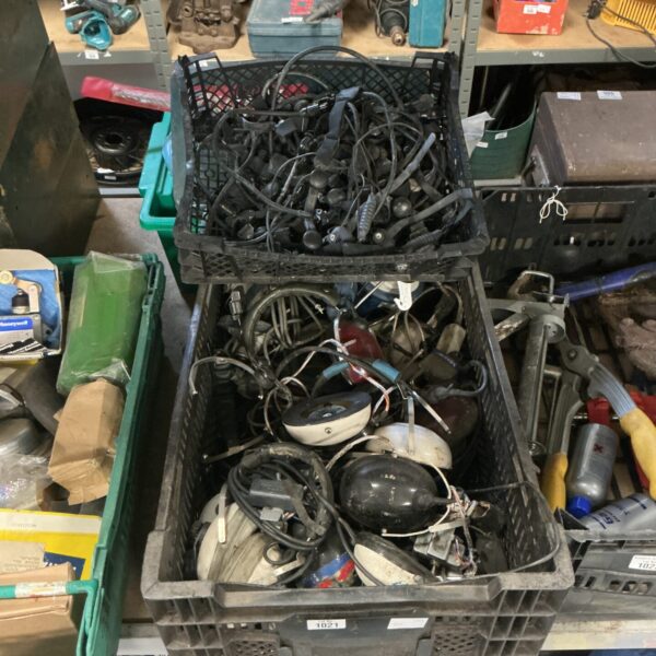 Crate of vintage military headsets and throat microphones for radio communication.