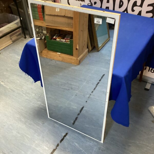 Rectangular wall mirror hanging on a blue background.