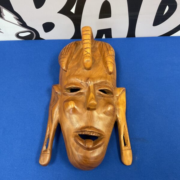Front view of a hand-carved Maasai warrior mask in dark wood.