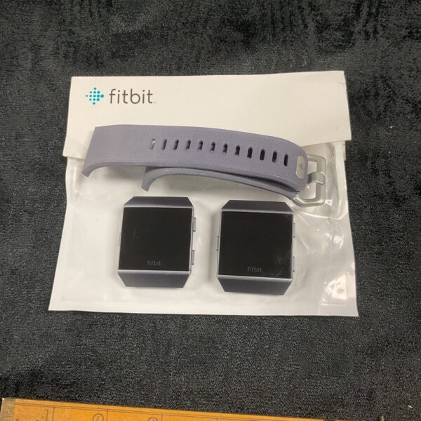 Two Fitbit watches and a strap in a box.