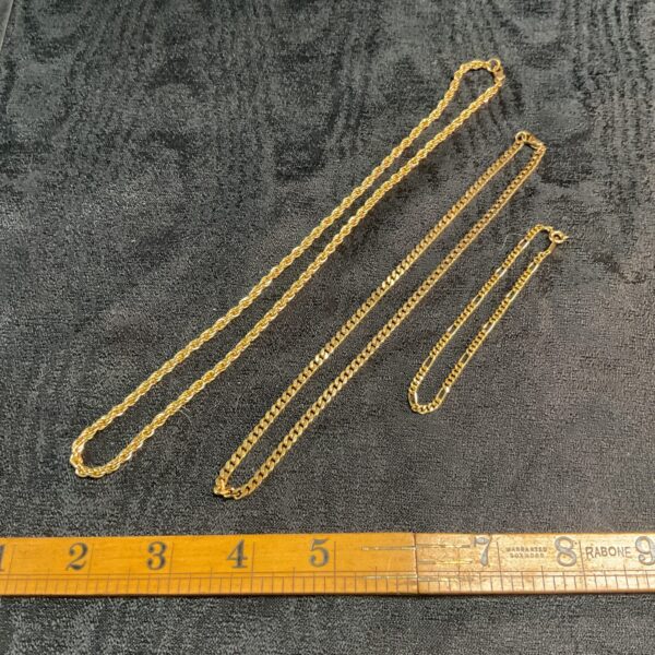 Two yellow gold rope chain necklaces on a measuring tape.