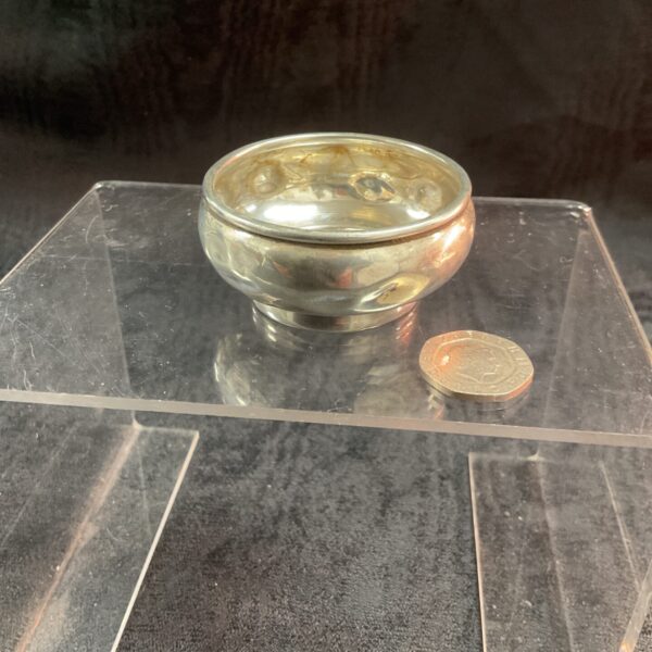 Antique silver relish bowl displayed on a clear stand.