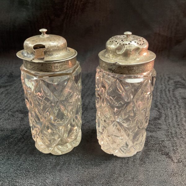 Antique Victorian silver top shakers with intricate detailing.