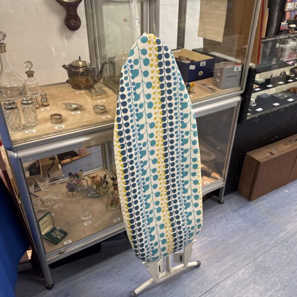 Vintage ironing board with colourful geometric patterned cover.