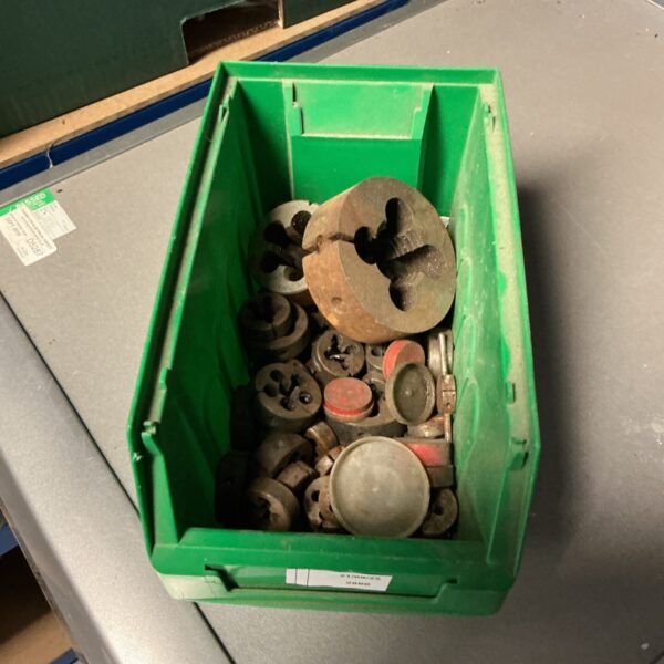 Box of assorted taps and dies for metalworking.