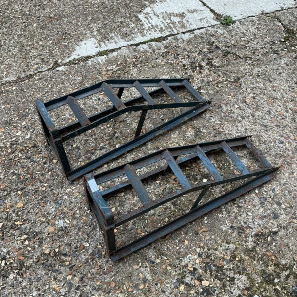 Pair of weathered steel car ramps for vehicle maintenance.