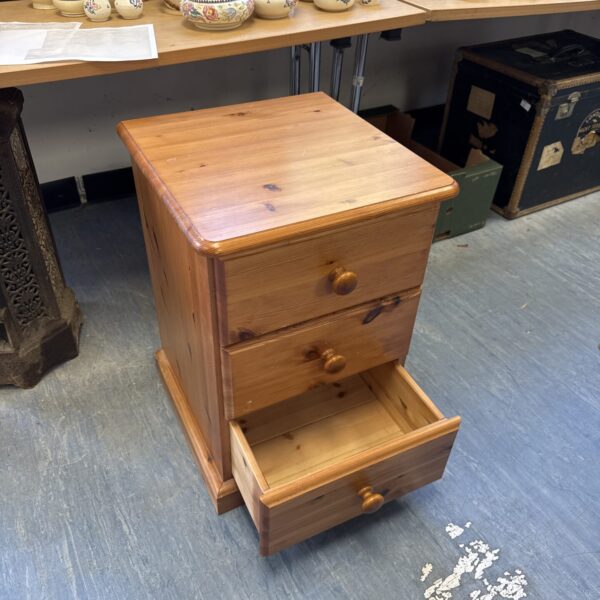 Antique pine three-drawer cabinet with wooden knobs.