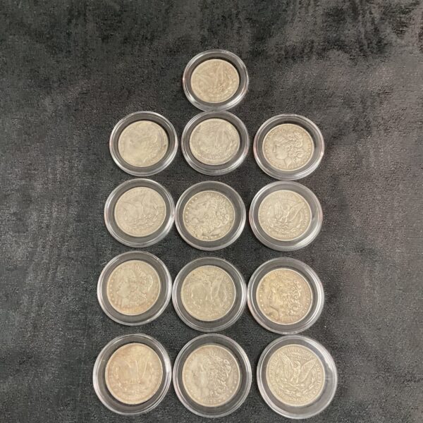 Lot of thirteen silver tone reproduction Morgan Dollar coins.