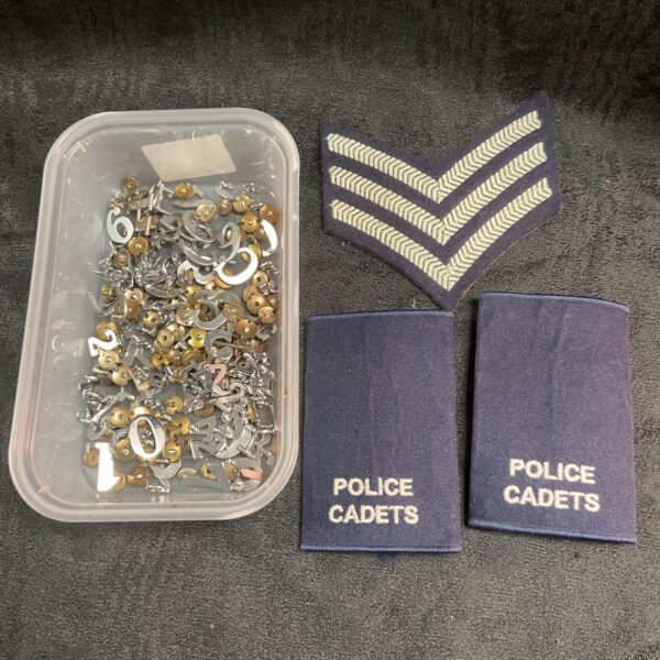 Tray of chrome police epaulette numbers and cloth badges for collectors.