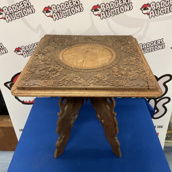 Front view of antique carved oak folding table with intricate details.