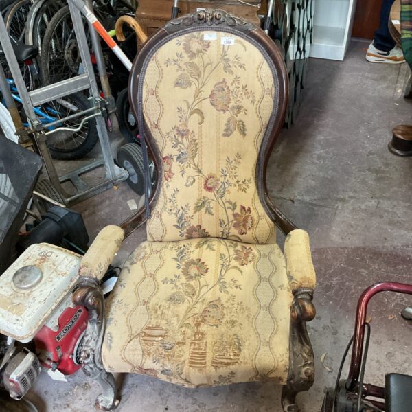 Antique floral balloon back nursing chair with curved armrests.