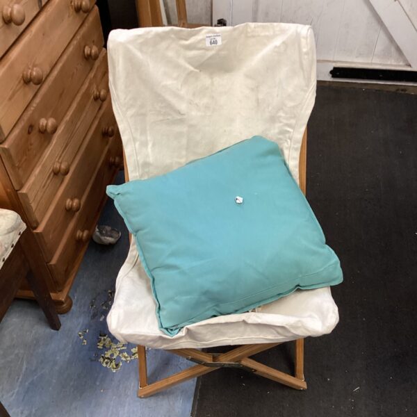 Vintage folding canvas chair with wooden frame, showing wear.