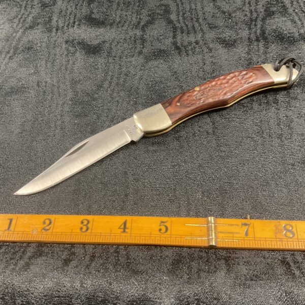 Open Case XX pocket knife with wood handle on ruler.