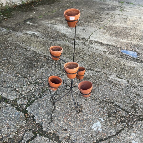 Tiered metal garden plant pot stand with terracotta pots.