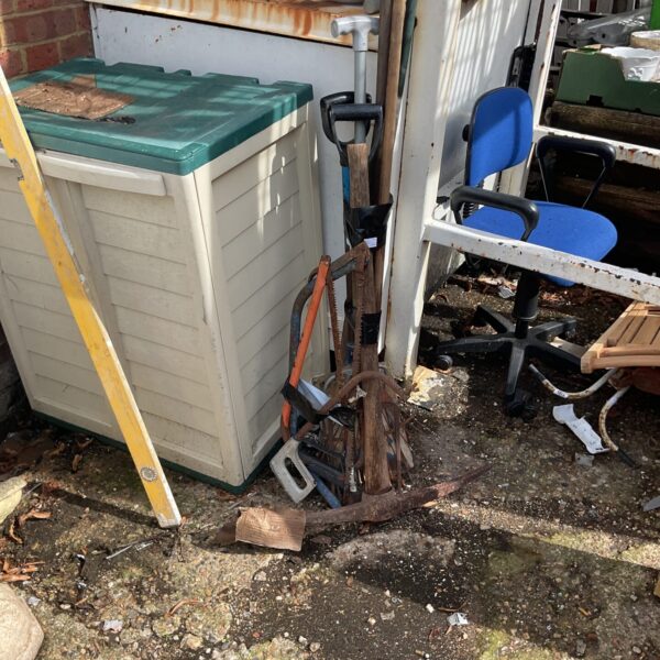 A collection of garden tools and equipment in a garden setting.