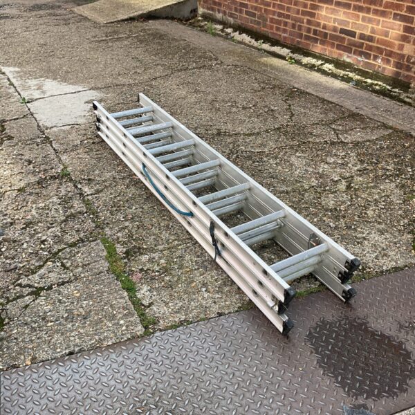 Silver aluminium extending ladder leaning against a wall.