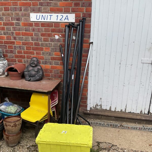 Metal clothing rail sections and spare parts in a garden setting.