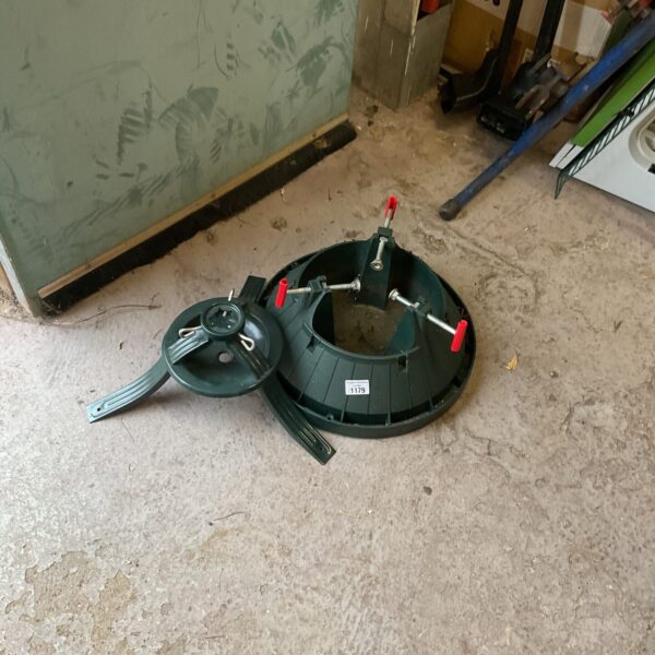 Green plastic Christmas tree stand with tightening screws.