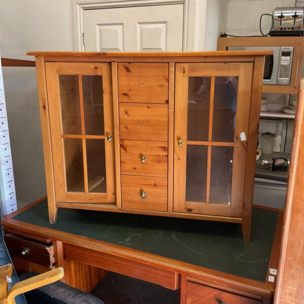 Vintage pine four-drawer sideboard with glass doors for storage.