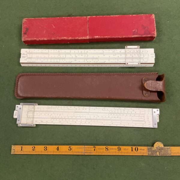 Vintage slide rules and cases on a green surface.