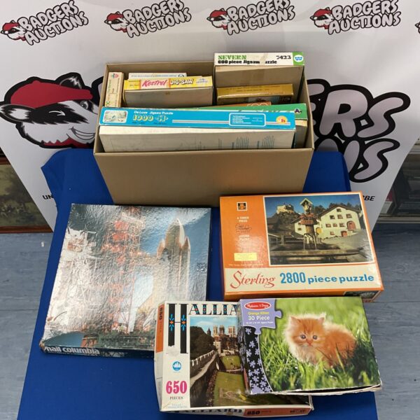 Vintage jigsaw puzzle lot with colourful boxes and pieces.