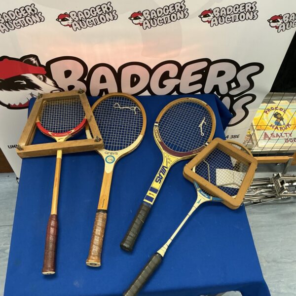 Four vintage tennis and badminton rackets with wooden frames.