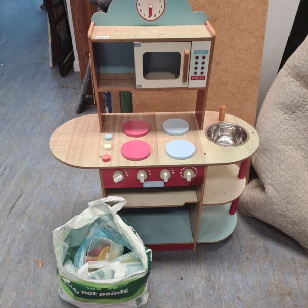 Front view of a colourful wooden play kitchen with accessories.