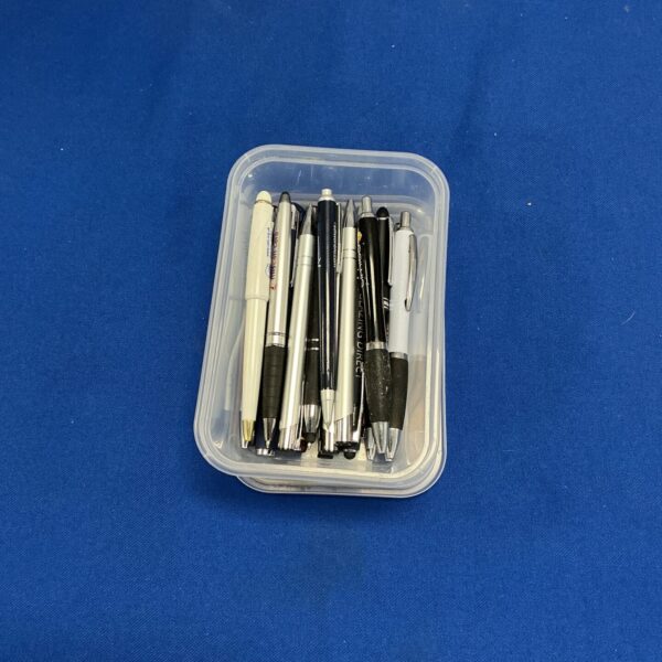 Clear plastic box filled with assorted pens and writing instruments.