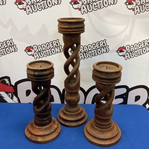 Three large carved wooden candlesticks with a twisted design.