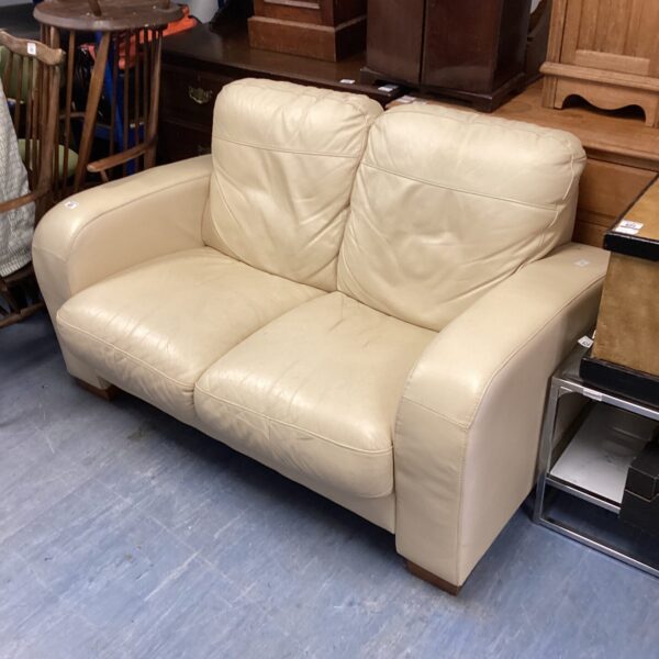 Cream leather two-seater sofa in good condition.