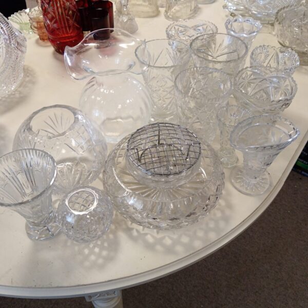 Large lot of vintage cut glass and crystal vases and bowls on display.