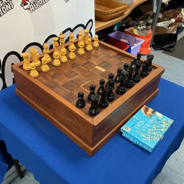 Handmade wooden chess set with detailed pieces on a dark board.