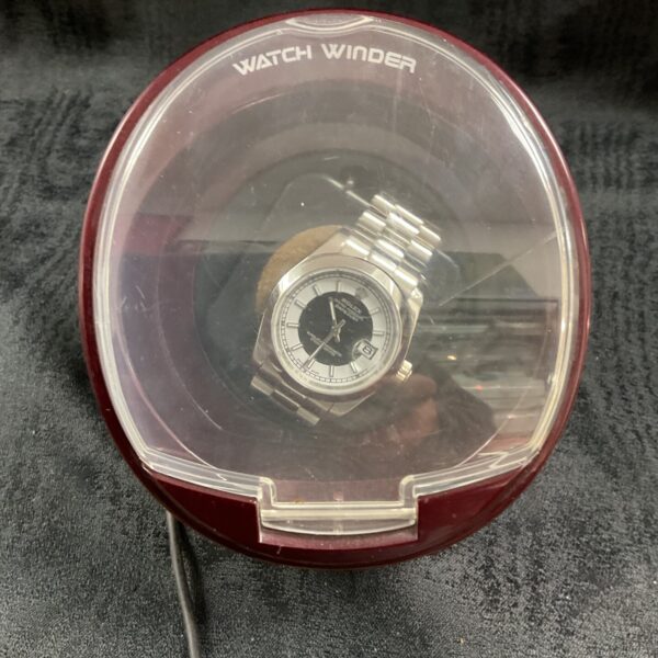 Clear plastic watch winder displaying a replica Rolex watch.