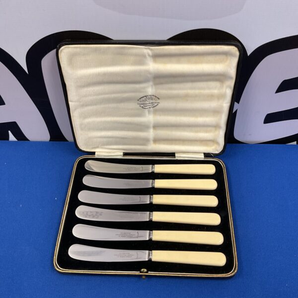 Vintage Goldsmiths Regent Street butter knife set displayed on velvet.