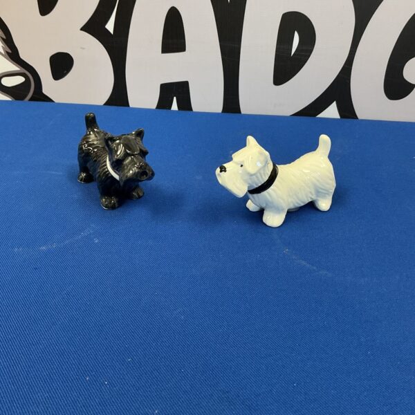 Vintage Whyte and Mackey dog salt and pepper pots on a dark surface.
