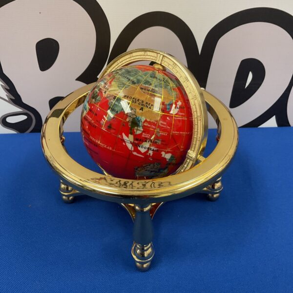 Antique gemstone globe on brass stand, detailed world map.