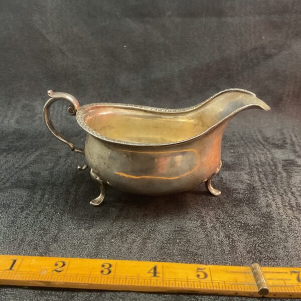 Antique sterling silver sauce boat with hallmarked details.