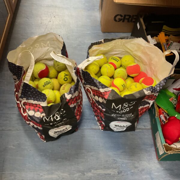 Two bags filled with a mixed lot of used tennis balls.