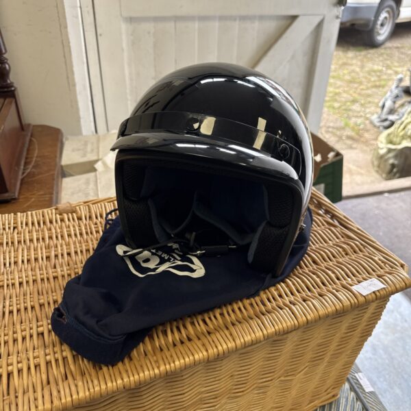 Black open face motorcycle helmet resting in a wicker basket.