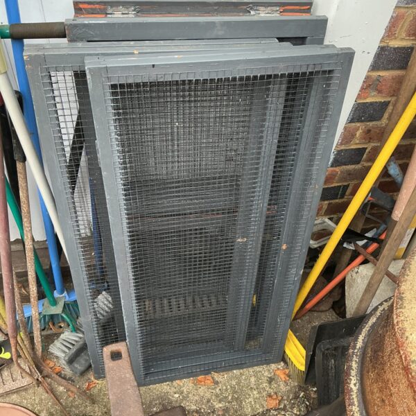 Wire mesh animal run cage for small pets in a garden setting.