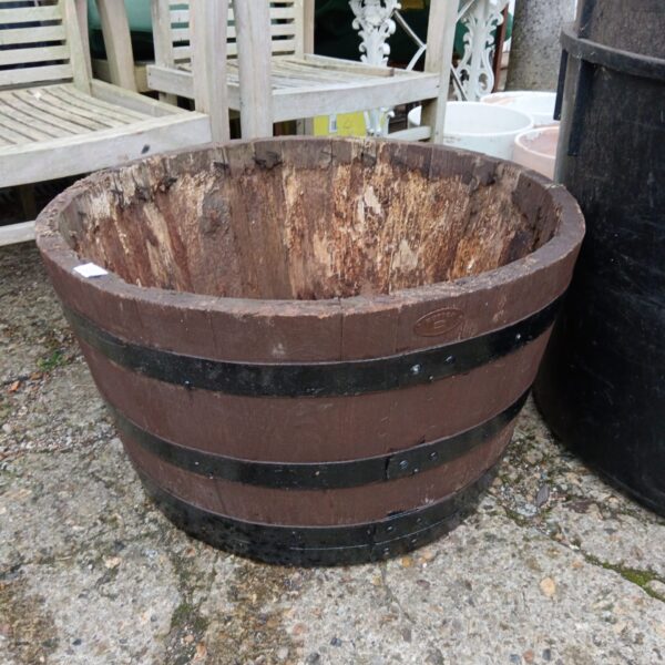Large wooden barrel planter for garden plants.