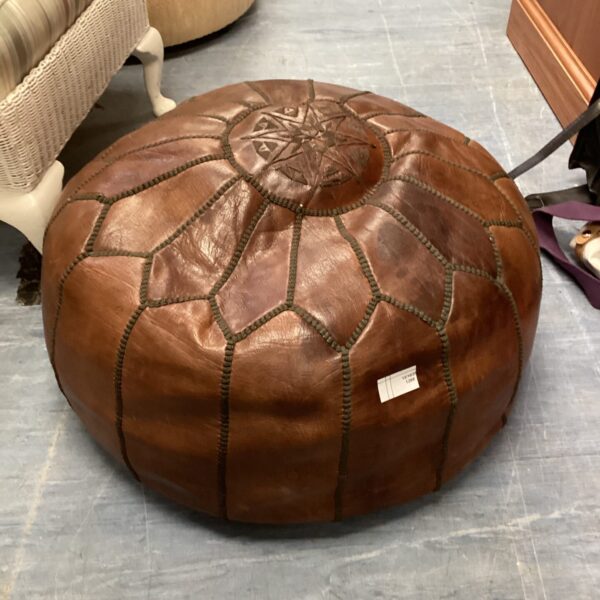 Detailed view of a handcrafted leather pouffe with intricate design.