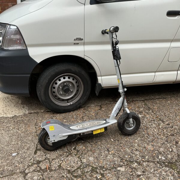 Side view of a blue Razor electric scooter with charger.