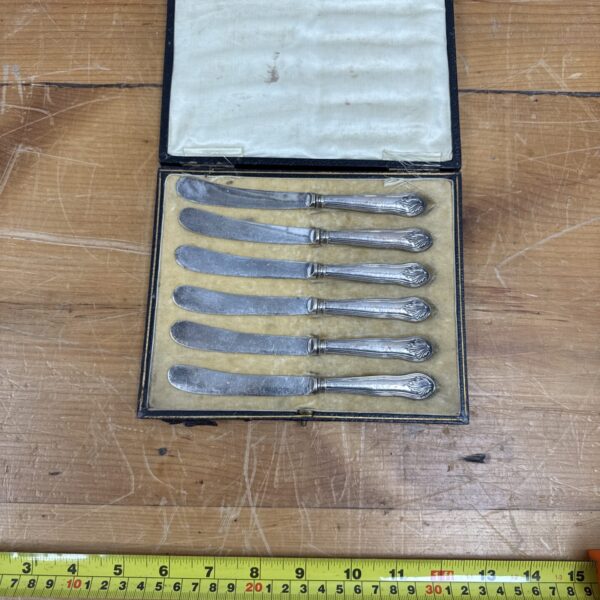 Cased set of six Victorian silver cake knives on a wooden surface.