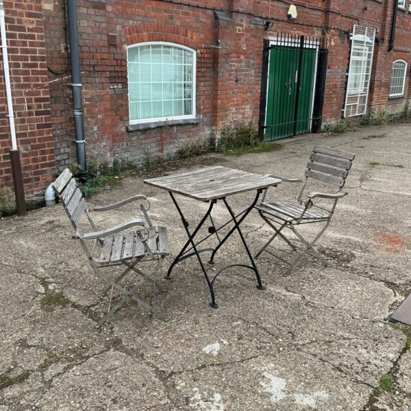 Vintage garden patio set with folding table and wooden chairs.