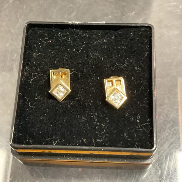 Close-up of 9ct gold CZ stud earrings on a dark background.