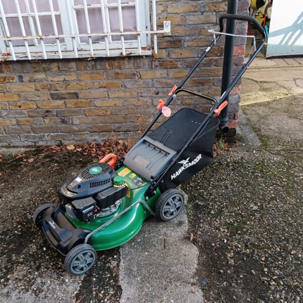 Green and black Hawksmoor petrol lawnmower in a garden setting.