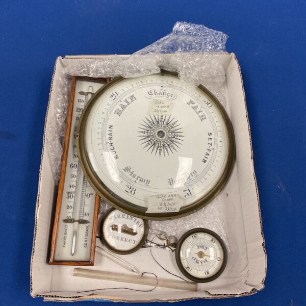 Antique brass aneroid barometer with thermometer, vintage weather instrument.