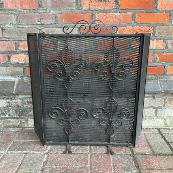 Antique iron firescreen with fleur de lis design for fireplace safety and decor.